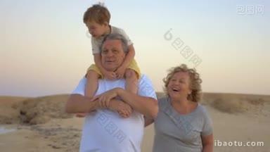 慢镜头中的爷爷和孙子在海滩上散步，爷爷把男孩扛在肩膀上